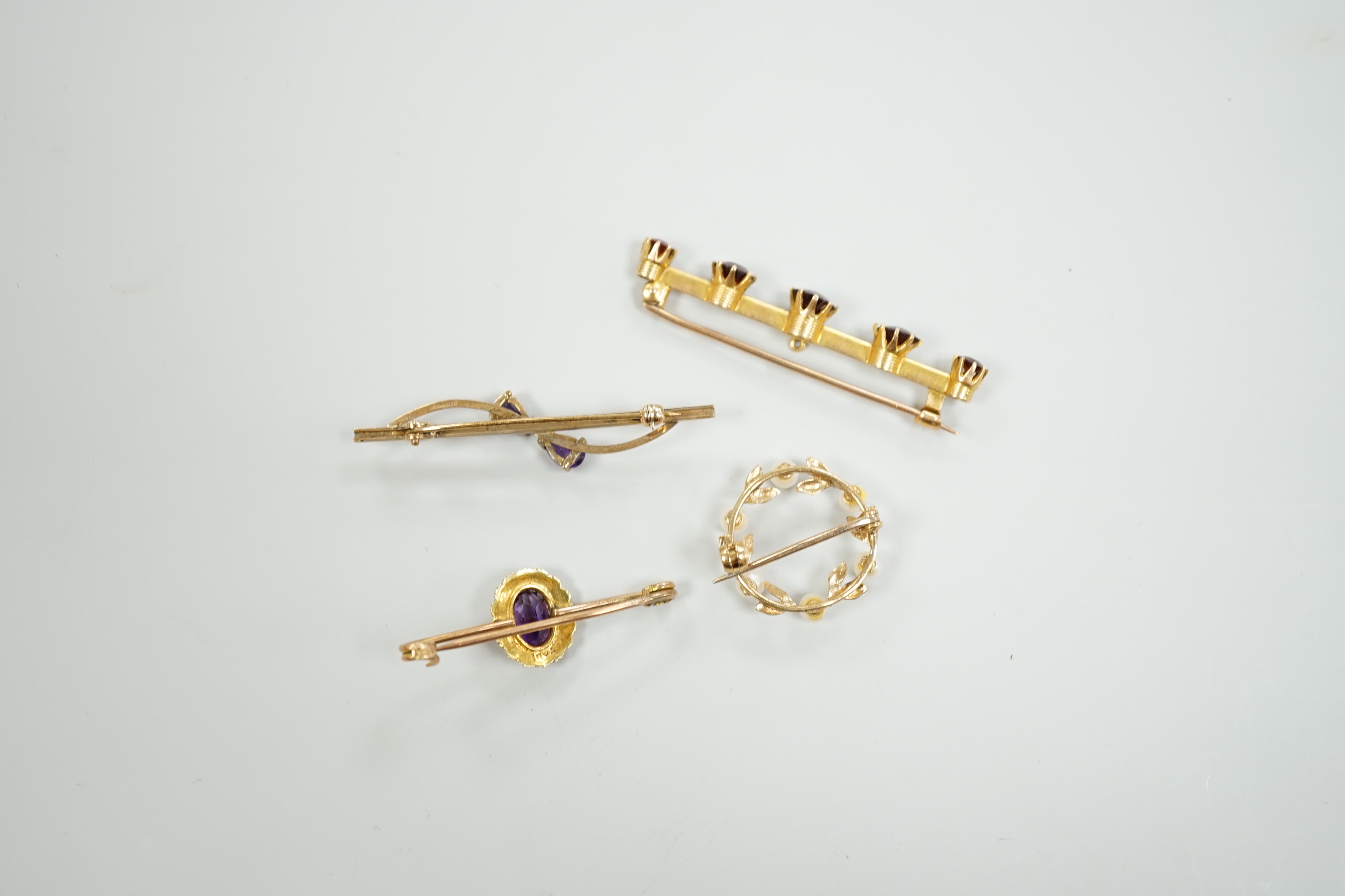 A 15ct and graduated five stone garnet set bar brooch, 48mm, a similar amethyst and seed pearl cluster set brooch and two other gem set brooches, including 9ct gold.
